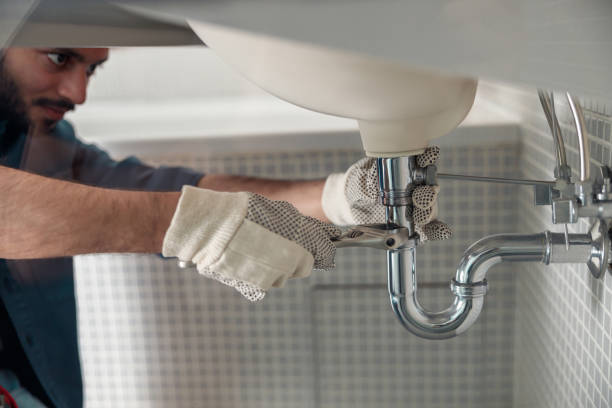 plombier Schaerbeek indien répare le robinet d’un évier à la salle de bain à l’aide d’une clé réglable 