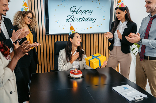 Group of people having an office birthday party for their female colleague.