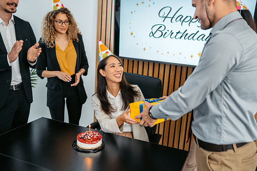 Group of people having an office birthday party for their female colleague.