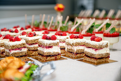 Close-up of cakes with fresh fruits and berries arranged in a row on a party table