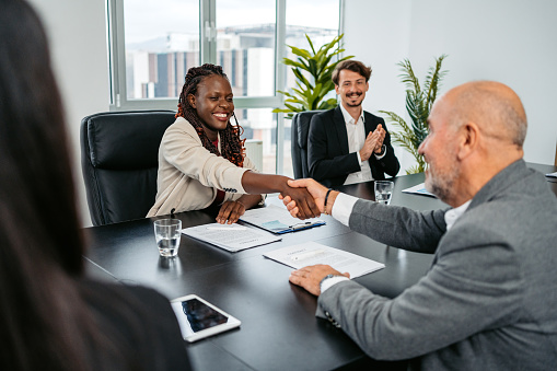 Group of people having a business meeting at the office. Two business colleagues shaking hands to seal the deal.