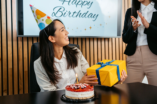 Young businesswoman celebrating her birthday with her colleagues in the office.