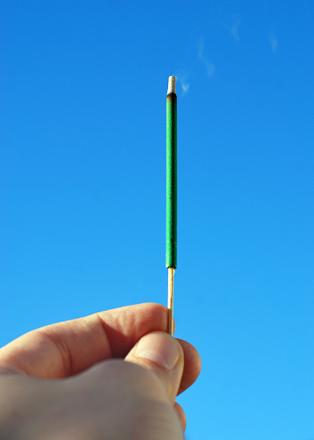 Closeup of a man's hand burning an incense stick.