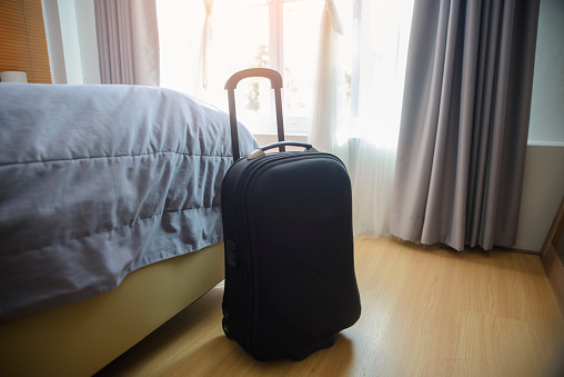 Luggage or Suitcase Bag with hat in Hotel room. Tourist depart from airport and arrive at resort bedroom to relax on vacation. Travel Domestic Concept.