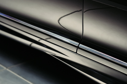 Close-up view of a modern luxury black car door with beautiful reflections. Exterior details. Abstract background