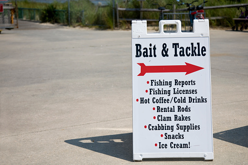 Information sign at the beach for retail convenience store, renting fishing rods, selling bait and tackle, crabbing supplies, and snacks.