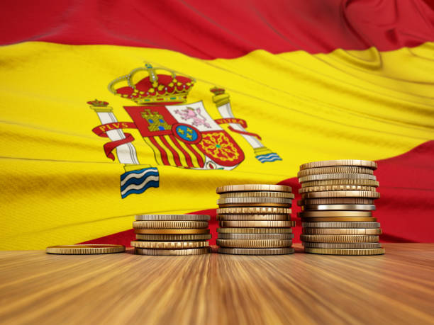Rising stack of coins with Spanish flag in the background. Economy, finance, interest rates concept stock photo