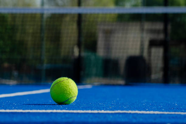 ein ball auf der bodenfläche eines blauen paddle-tennisplatzes - court building stock-fotos und bilder