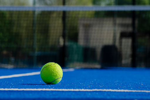 a ball on the surface of a blue paddle tennis court