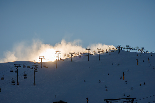 Snow cannons create a fog on the mountains in the ski resort