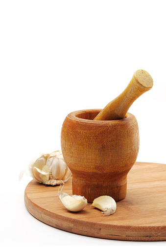 Garlic on wooden cutting board, isolated on white background. Copy space. No people.