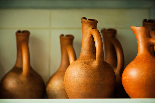 Wine jugs of terracotta color on the rack, close-up view, soft focus