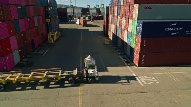 Drone Flight Between Rows of Containers in Busy Shipping Terminal