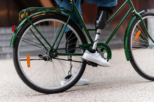 View of a man with prosthetic legs and white sneakers. Sitting on his bicycle