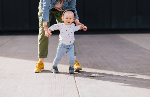 istock Mom Helping Her Daughter Walk Outside on a Sunny Day 1448889617