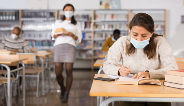 istock Woman wearing mask studying in public library 1448891414