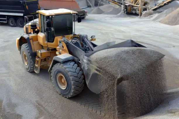 A sand dump wheel loader unloads sand into a pile in a quarry