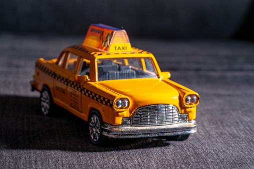 miniature model of yellow new york taxi on dark night background. black and white image