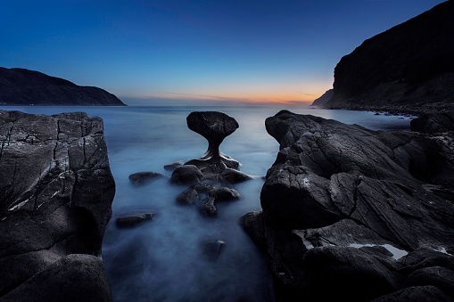 A long exposure shot of the kannesteinen rock and sea in a beautiful rocky coast in Norway at sunset