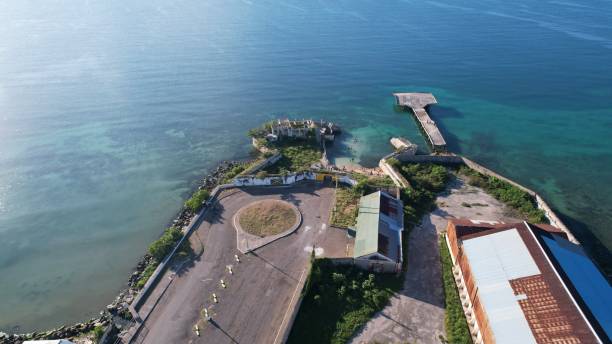 istock Drone shot over a warehouse with some greenery on the shore, pier and sea under sunlight 1448903375