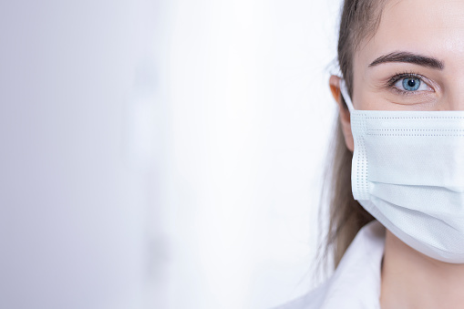 Half face portrait of a woman doctor with surgical mask.