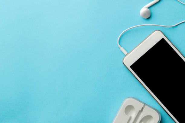 istock Smartphone. White phone and headphones on a bright light blue background. top view. space for text 1448912600