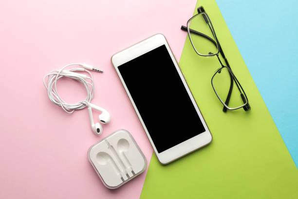 istock Smartphone. White phone and headphones and glasses on a bright multi-colored background. top view. 1448912641