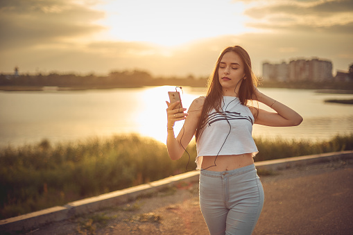 girl listening to music with smartphone walking in the city with headphones smiling - relax, youth, emancipation concept.