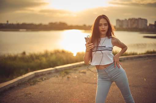 Young beautiful caucasian girl listening to music with smartphone walking in the city with headphones smiling - relax, youth, emancipation concept.