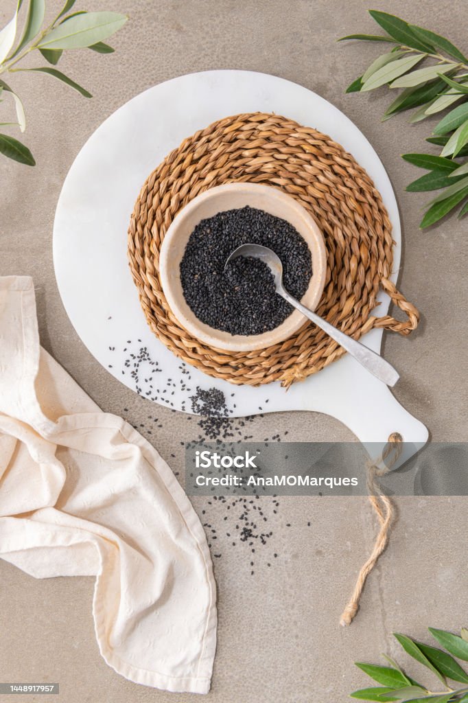 Black sesame seeds or gergelim in ceramic bowl with spoon in kitchen countertop. For healthy food and diet concepts. Top view Breakfast Cereal Stock Photo