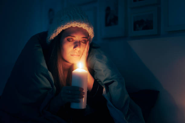 istock Unhappy Woman Feeling Cold Sitting in the Dark Using a Candle 1448922891