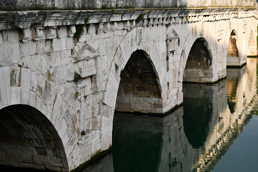 Arches of the Tiberius Bridge in Rimini, Italy, and their reflection in the Marecchia river.