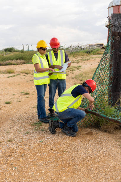 istock Three industrial workers at work in front of a refinery 1448923169