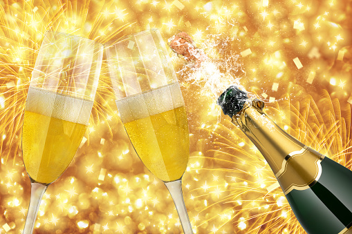 Merry Christmas and Happy New Year, celebration background with two glasses and uncorked champagne bottle splashing.