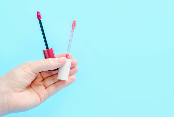 istock Female hand holds lipstick brushes close-up on blue background copy space. 1448931692