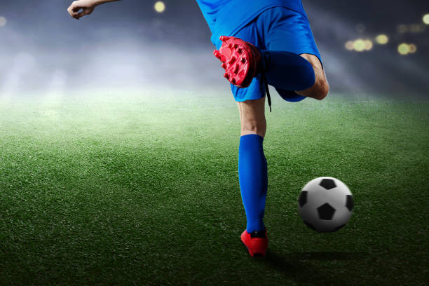 вид сзади футболиста в синей майке, пинающего мяч - indonesia football стоковые фото и изображения