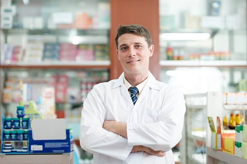 Pharmacist working in drugstore looking at camera
