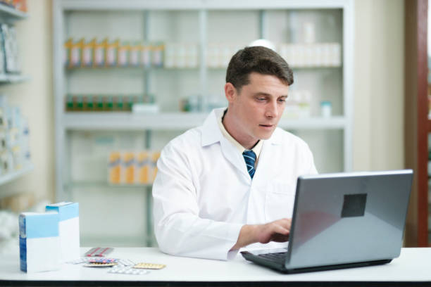 farmacêutico do sexo masculino que trabalha na farmácia moderna usando laptop. - cyberspace doctor healthcare and medicine prescription medicine - fotografias e filmes do acervo
