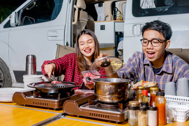 istock Asian couple sitting while grilling barbeque enjoying camp activity 1448943448