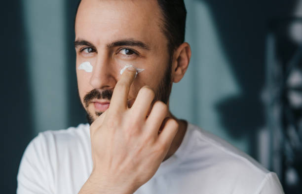 istock Handsome young man applying nourishing cream and looking at camera while standing at home. Enjoying morning routine. Beauty treatment. Dermatology, cosmetology. 1448955989