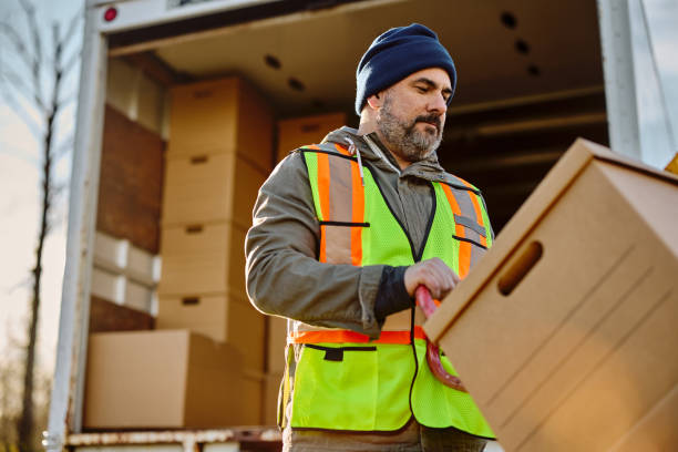 istock Mid adult delivery man loading cardboard boxes in a truck. 1448959004