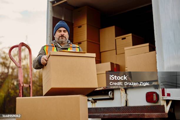Male Worker Unloading Cardboard Boxes From Delivery Van Stock Photo - Download Image Now