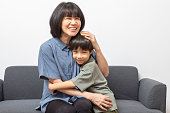 Asian woman cuddling her little son smile and look at camera.