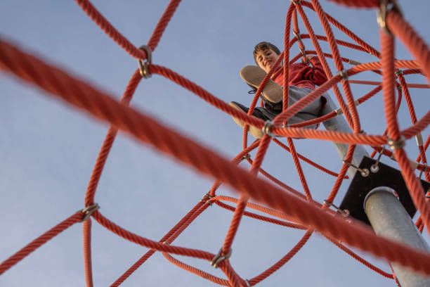 istock kid on the top looking down after climbing the ropes in a playground 1448968582