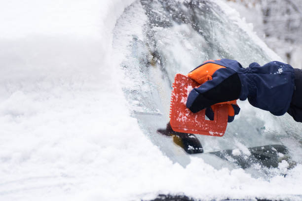 istock Man cleans his car after a snowfall. Cleaning snow from windshield, Scraping ice, Winter car window cleaning 1448971245