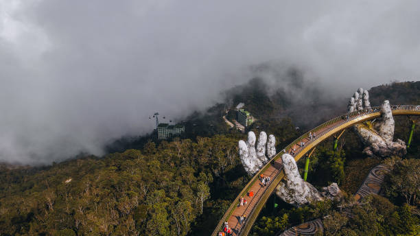 Da Nang city, Vietnam - November  18, 2022:Tourists walk on the Golden Bridge in Ba Na Hills, supported by a pair of giant hands. The bridge located 1,400 meters above sea level with hill scenery