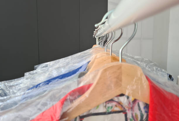 Hangers with clean clothes in laundry room. Clothing care and dry cleaning services