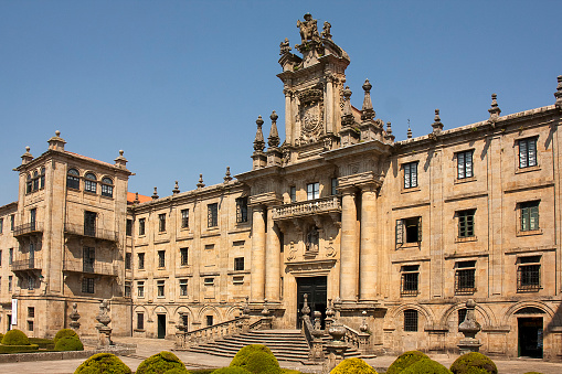 Stone facade of San Martín Pinario monastery in old town Santiago de Compostela with staircase and garden in the foreground. A Coruña province, Galicia, Spain.