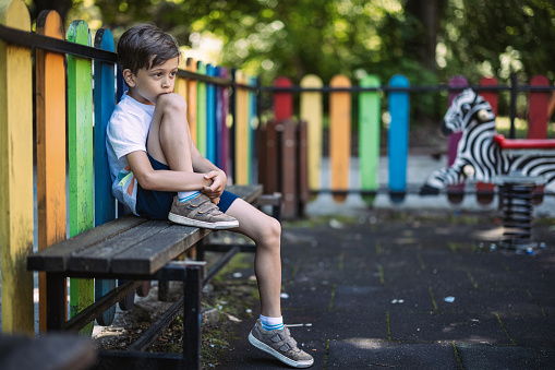 Niño triste sentado en un banco photo