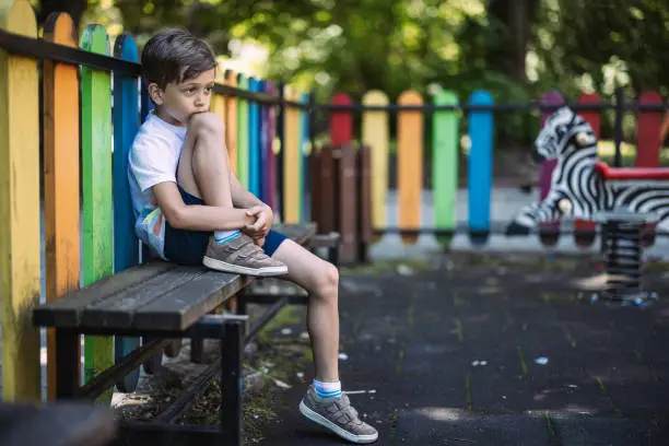 Photo of Sad boy sitting on a bench